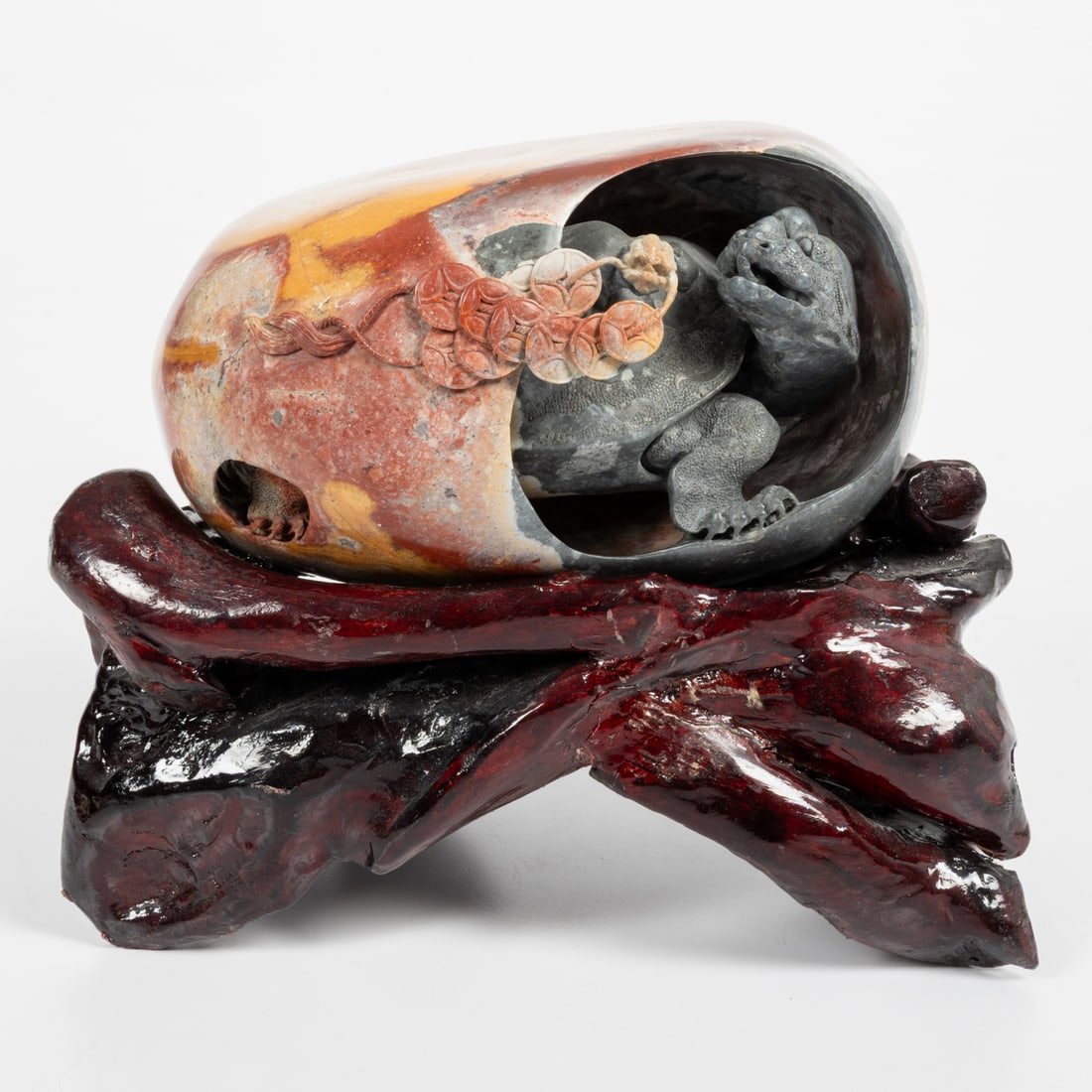 A Chinese Colored Hardstone Sculpture: A Chinese Carved Colored Hardstone Sculpture of a Turtle in a Egg, 20th Century, Having a lacquered hardwood stand. Egg, H: 4 1/2 x L: 7 x W: 4 3/4 in. Stand, H: 4 3/4 x L 9 1/2 x W: 4 3/4 in.