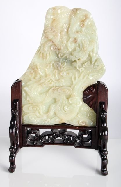 A Chinese Celadon and Russett Jade Table Screen: A Chinese Celadon and Russett Jade Table Screen Having Carved Dragon and Flaming Pearl Motif, 20th Century, Together with a carved wood stand. Dimensions: h: 13 x w: 9 x d: 3/4 in.