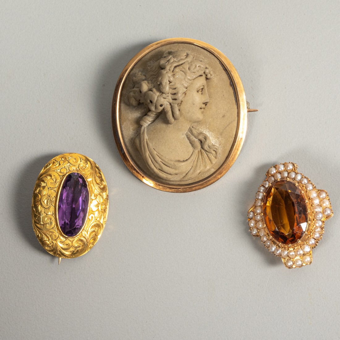 Three 14 kt Yellow and Rose Gold Victorian Brooches: Three 14 kt Yellow and Rose Gold Victorian Brooches, Comprising a citrine and seed pearl brooch, an amethyst brooch, and a carved lava cameo brooch. Lava Brooch approx: H: 1 3/8 x W: 1 1/8 in. Citrine