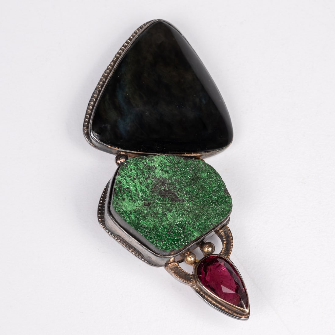 Sterling Silver, Gold & Gemstone Brooch: A Sterling Silver, 18kt & 14kt Yellow Gold and Gemstone Brooch, Velvet Obsidian, Pink Tourmaline & Uvalite gemstones, designed by Cynthia Mann. H: 2 3/8 x W: 1 1/8 in.