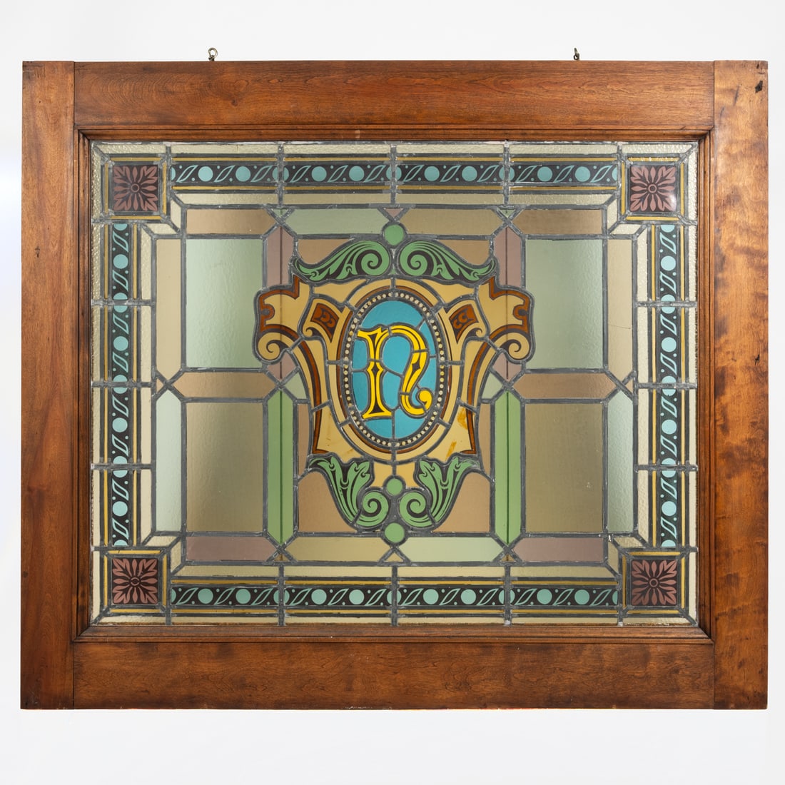American Leaded Stained Glass Window: An American Leaded Stained Glass Window, Central monogram, N. Framed with hanging hooks on top frame. H: 49 1/4 W: 57 in.