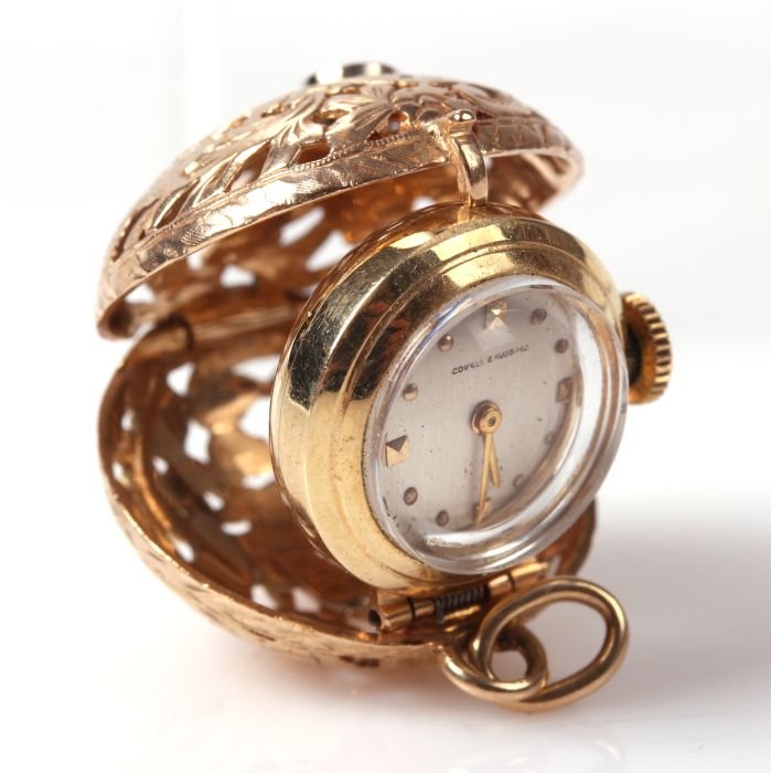 A 14kt. Yellow Gold and Diamond Clock Pendant by Cowell: A 14kt. Yellow Gold and Diamond Clock Pendant by Cowell and Hubbard, 20th Century, The watch is contained in a hinged, pierced ball accented with a 0.25 ct. round brilliant cut diamond with a J color