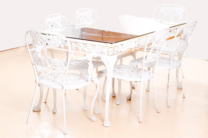 A Louis XV Style Cast Aluminum Garden Table with: A Louis XV Style Cast Aluminum Garden Table with Mirrored Top and Six Chairs, 20th Century, Comprising of two armchairs and four side chairs. Table dimensions: h: 29 1/4 x w: 66 x d: 32 in. Armchairs 