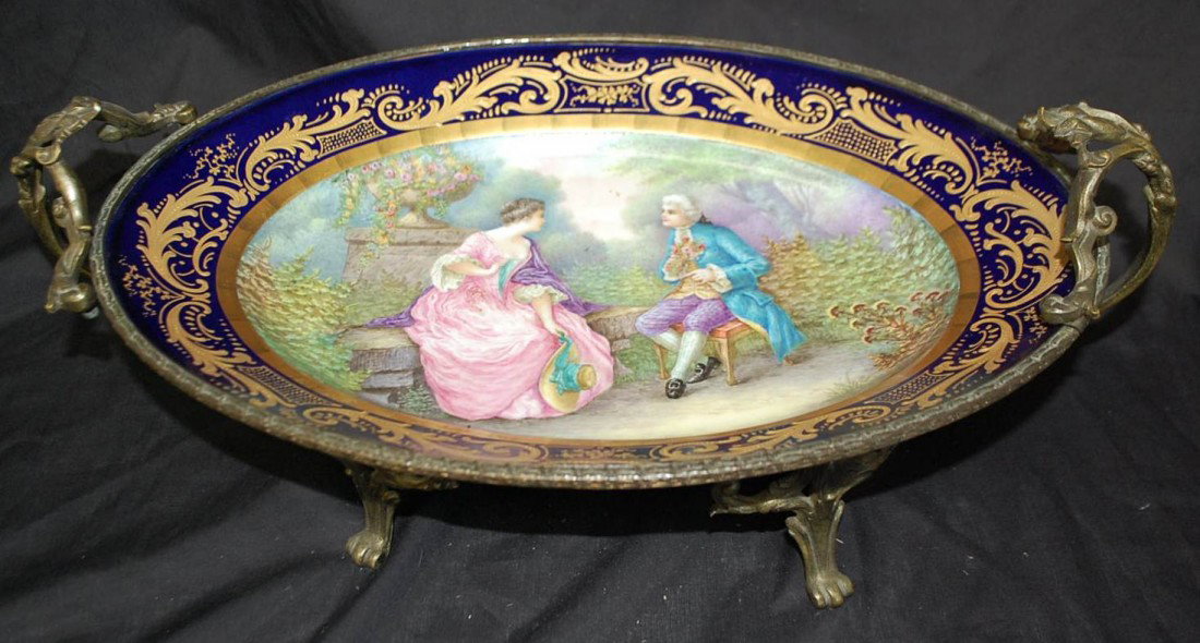 063: FRENCH OVAL PORTRAIT CENTERPIECE: GARDEN SCENE SIGNED GUY LOWER LEFT, BRONZE FOOTED BASE SURROUNDS PORCELAIN, 19"W, 11"D, 7"TALL, marked with Sevres blue mark on bottom