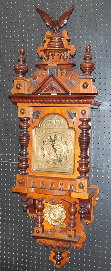 GUSTAV BECKER WALNUT WALL CLOCK: EAGLE CREST, BRASS DIAL, CHERUB PENDULUM, 16"W, 8"D, 50"TALL