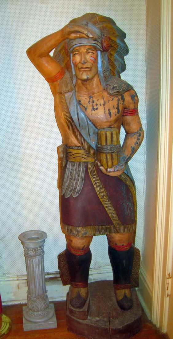 LIFESIZE CARVED WOOD CIGAR STORE INDIAN: FULL HEADRESS, GROUP OF CIGARS ON ROUND WOOD BASE FROM HISTORIC POTTER HOUSE