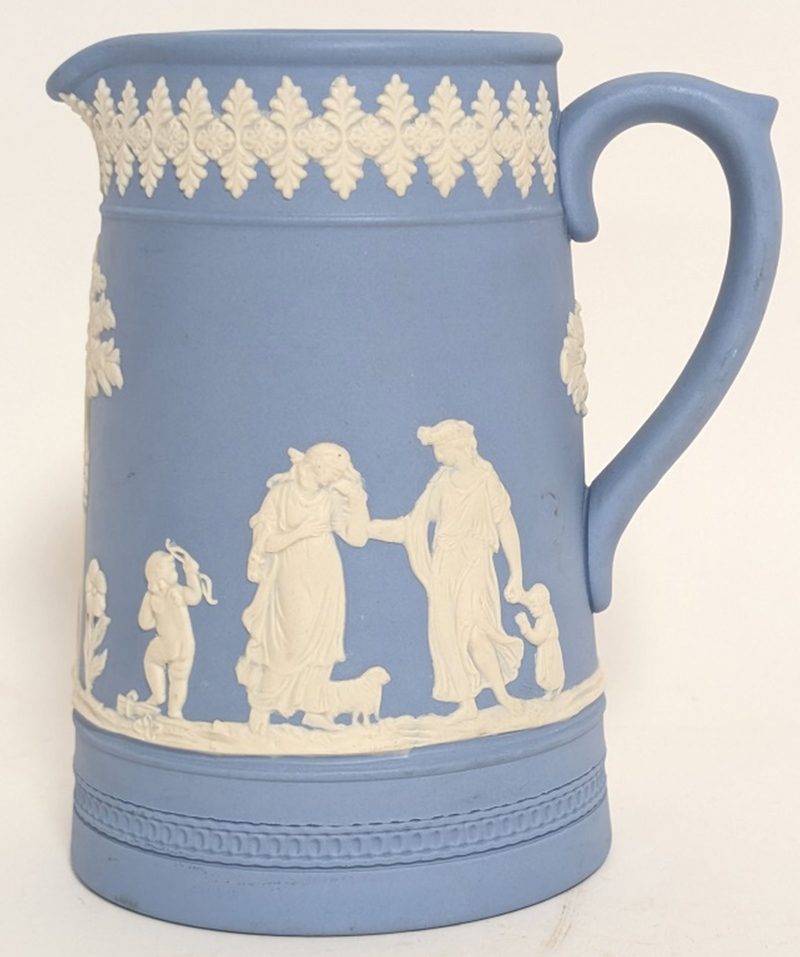 Dudson Hanley Blue Jasperware Pitcher: Dudson Hanley blue jasperware pitcher. This type of ceramic is known for its matte finish and white relief decorations, typically featuring neoclassical figures. 6H x 5W x 3.5D". Manufacturer: The pit