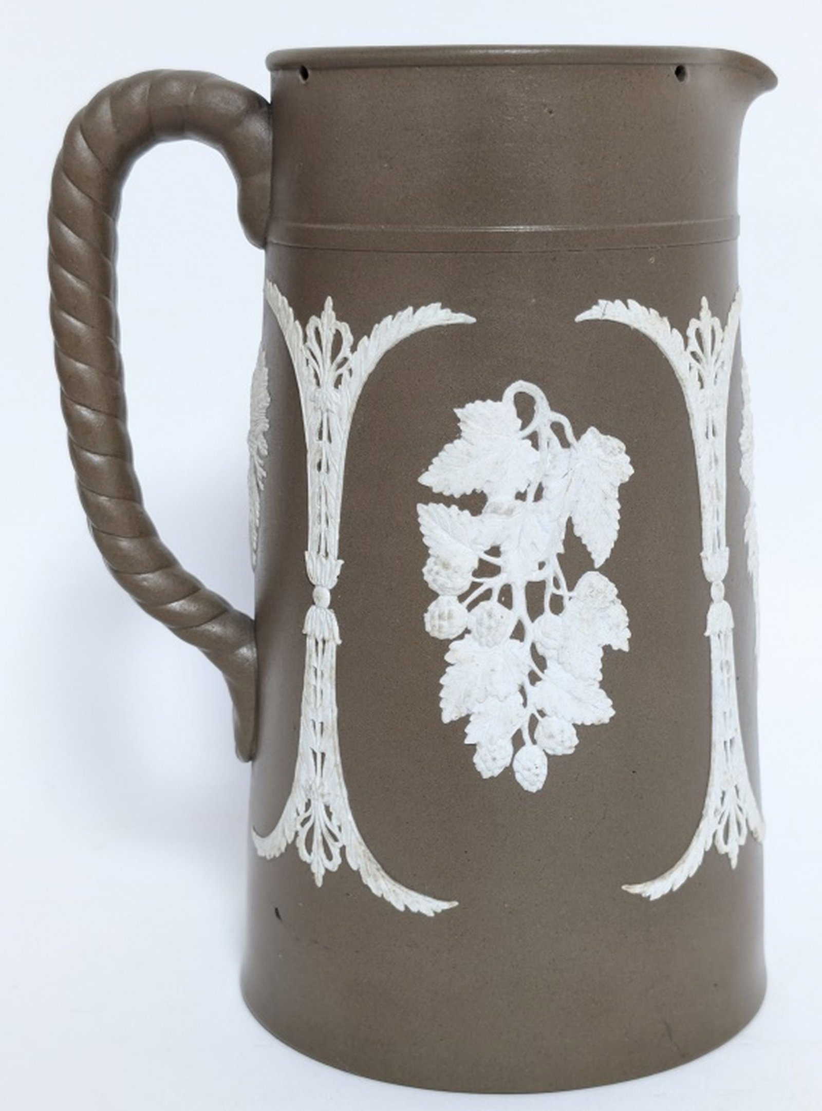 Antique Dudson Jasperware Pitcher: The image shows an antique Dudson brown jasperware pitcher or jug. This type of stoneware, known for its matte finish and white relief decoration, was developed by the Dudson potteries in Staffordshir