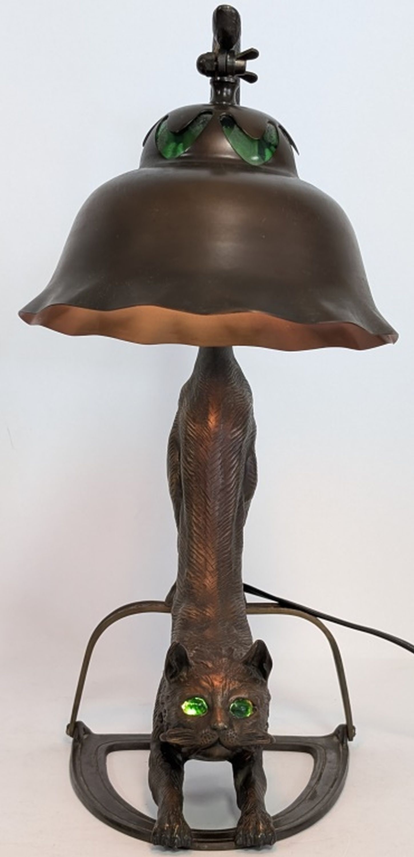 Art Nouveau Bronze Figural Cat Table Lamp: Charming Art Nouveau bronze figural table lamp modeled as a stretching cat with green glass inset eyes supporting a stylized shade with matching green glass cabochon accents. The sculptural design com