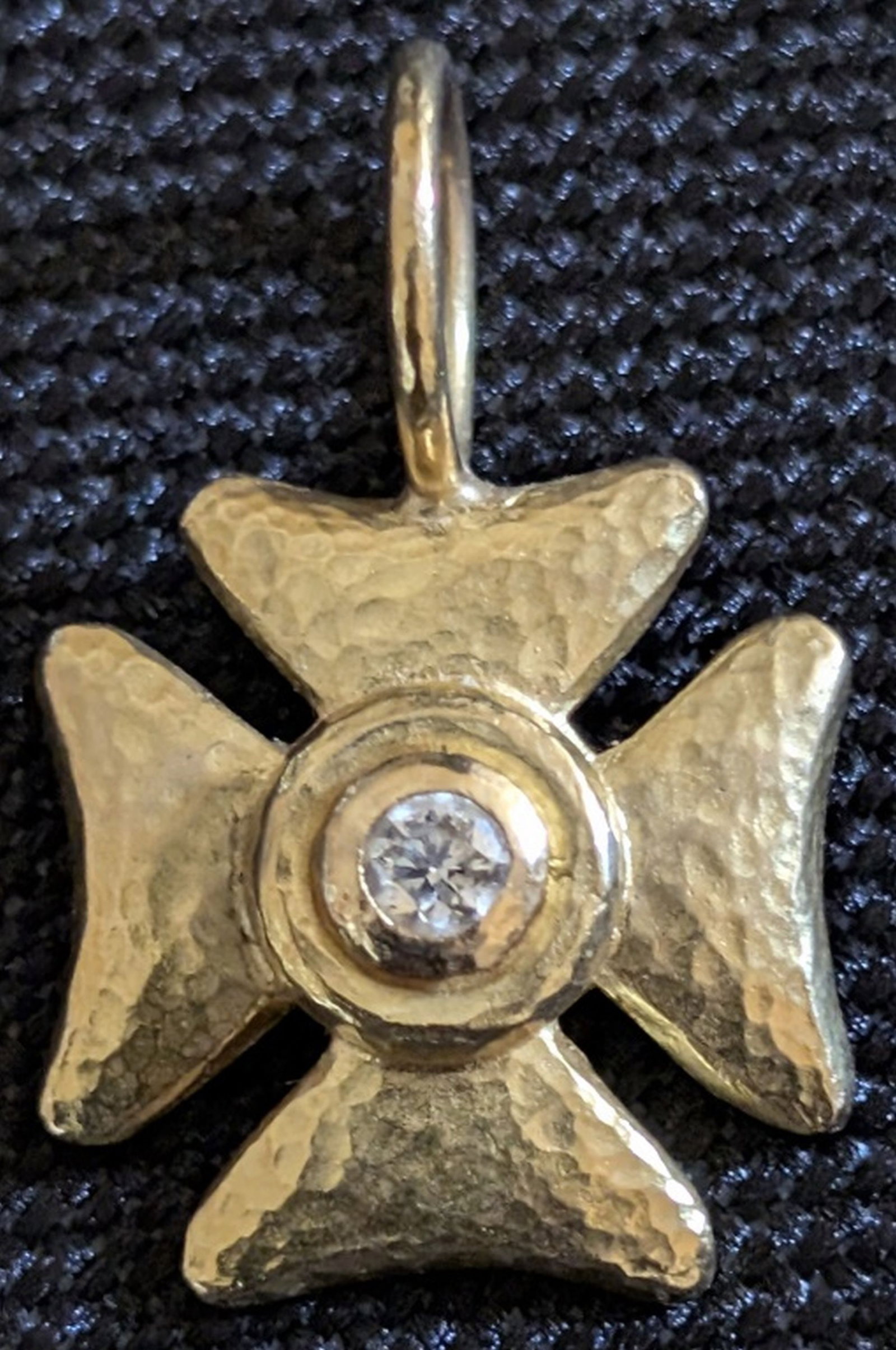 19K Gold and Diamond Maltese Cross Pendant: A distinctive 19K yellow gold pendant modeled as a stylized Maltese cross with a hand-hammered textured surface and central bezel-set old-cut diamond. The cross displays a sculptural, artisan-crafted 