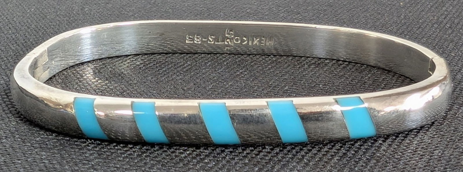 Sterling & Turquoise Hinged Bangle Bracelet: Sterling Silver and Turquoise Inlay Hinged Bangle Bracelet. Weight: 30.2 grams Approximate Size: 2.75 inches x 2.25 inches interior opening; approximately 0.25 inch wide. Elegant sterling silver hinge