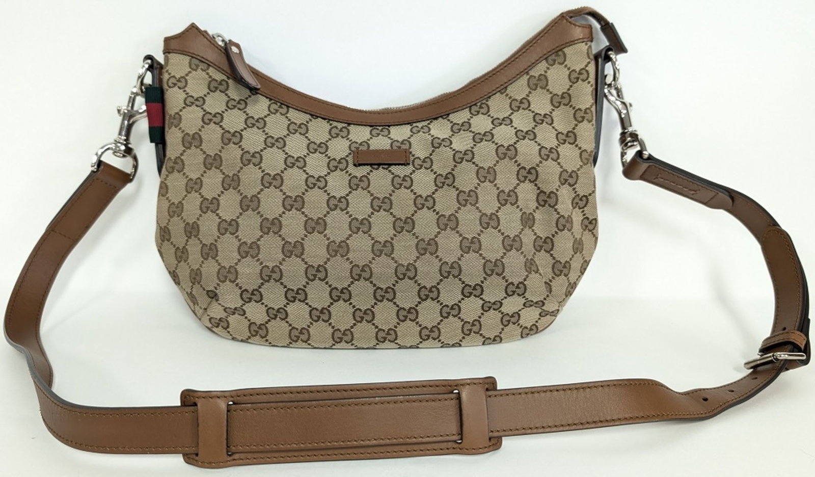 Gucci GG Canvas Crossbody / Shoulder Bag: Elegant Gucci crossbody bag crafted in the house’s signature beige and ebony GG monogram canvas with brown leather trim, adjustable leather shoulder strap, silver-tone hardware, and zip-top clos