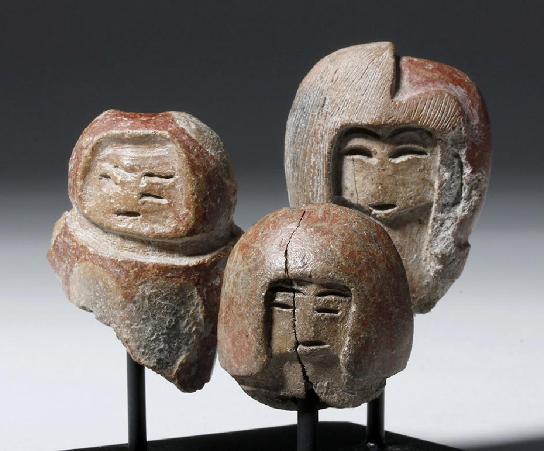 Group of 3 Valdivian Pottery Venus Heads: Pre-Columbian, Ecuador, Valdivian culture, ca. 3500 BCE. A trio of reddish pottery heads with thin slits for eyes, brows, and mouths, and bulbous hair. These fired clay figures were produced, starting