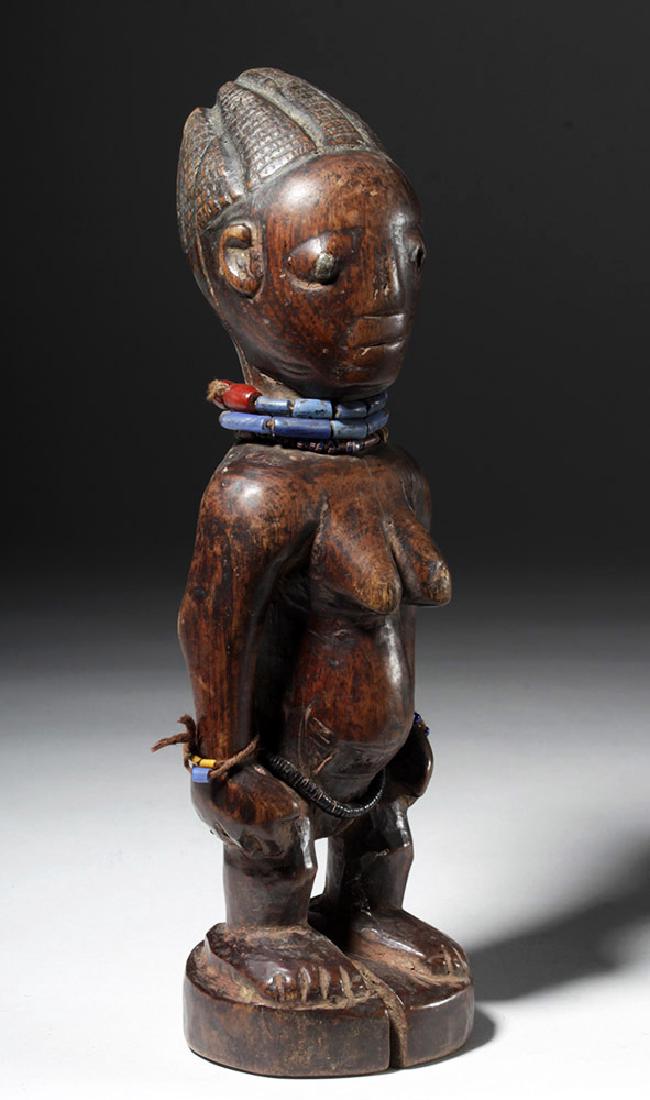Superb African Carved Wooden Ibeji Female Twin: West Africa, Nigeria, Yoruba peoples, ca. early 20th century CE. A female Ere Ibeji twin figure, hand carved to represent a deceased twin, standing with her hands placed upon her hips, upon an integra