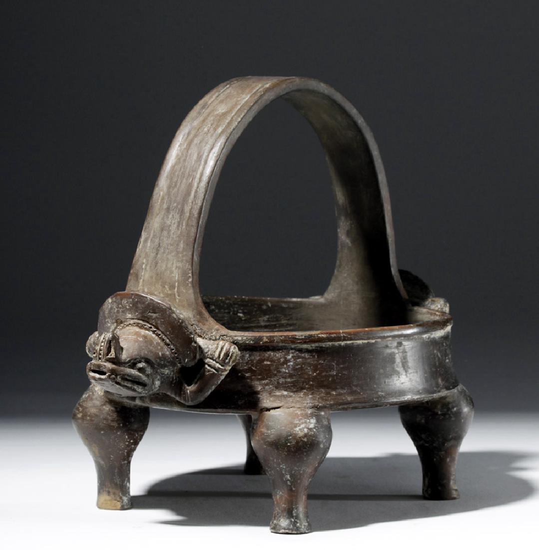 Rare Tairona Pottery Blackware Quadruped Bowl: Pre-Columbian, Colombia, Tairona region, ca. 1000 to 1550 CE. A low blackware bowl with a tall strap handle. Standing on four anthropomorphic legs, the vessel has, at the base of each end of the handl