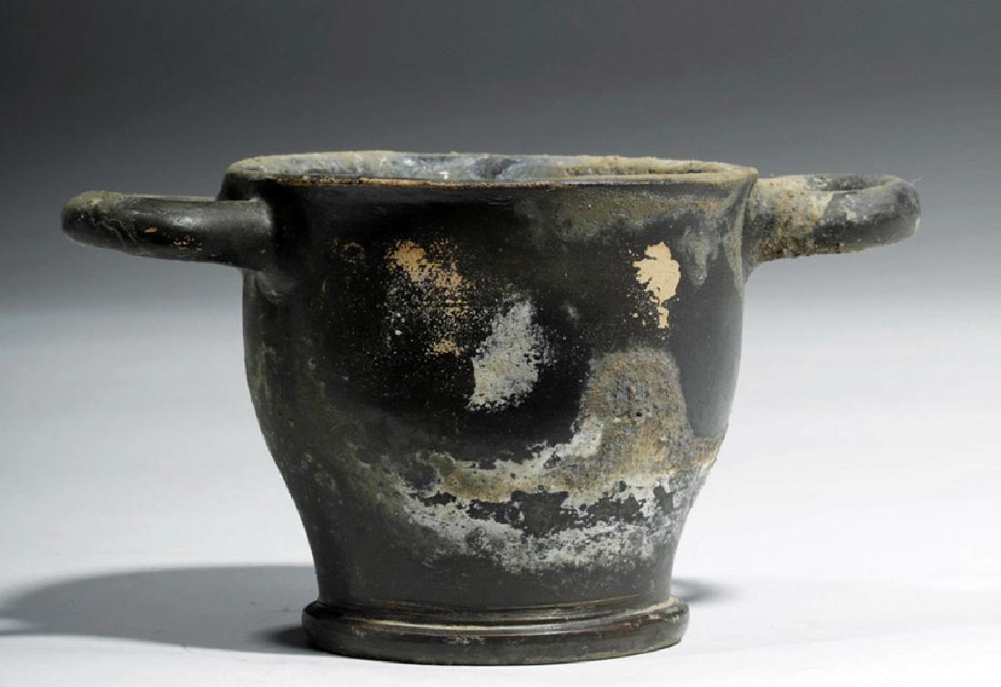 Greek South Italic Blackware Drinking Cup: Raise a glass! Magna Graecia, southern Italy, Apulia, ca. 430 to 300 BCE. A well-proportioned and symmetrical blackware skyphos for drinking wine with twin horizontal loop handles. The underlying clay