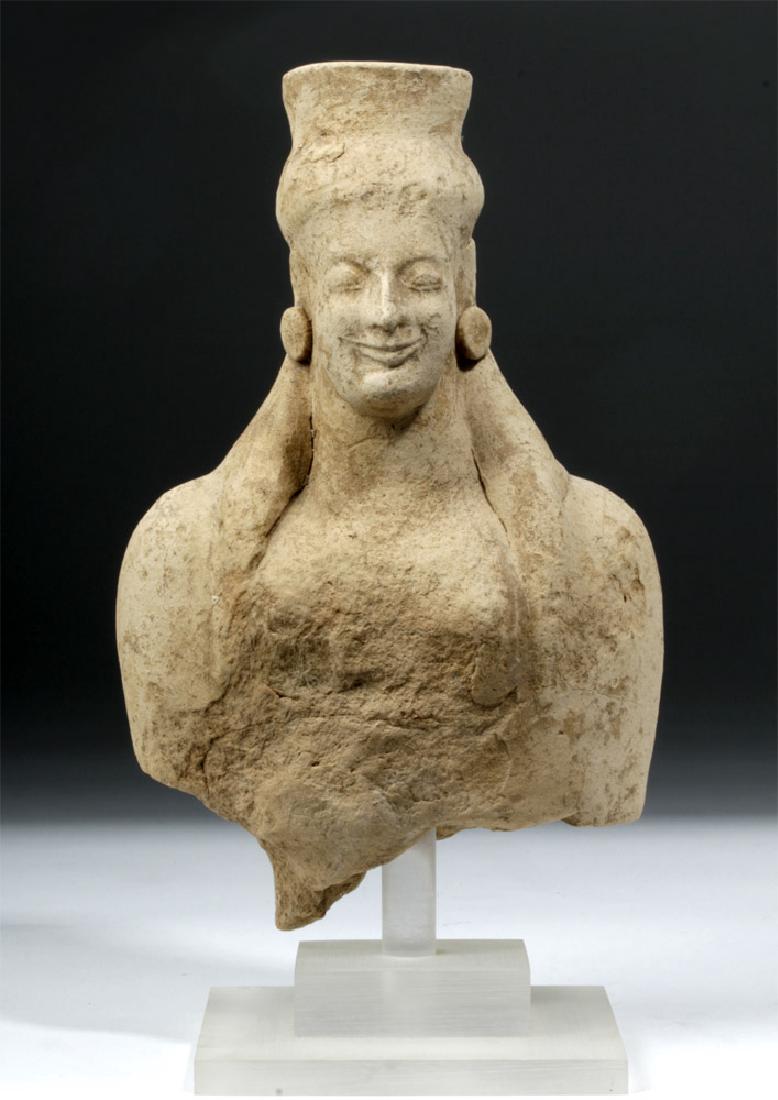 Archaic Greek Earthenware Votive of Goddess: Greece, Archaic Period, ca. 6th century BCE. A mold-made votive head and torso of a woman. She is portrayed as nude aside from a polos crown over her long hair. The Greeks adopted the polos from the a