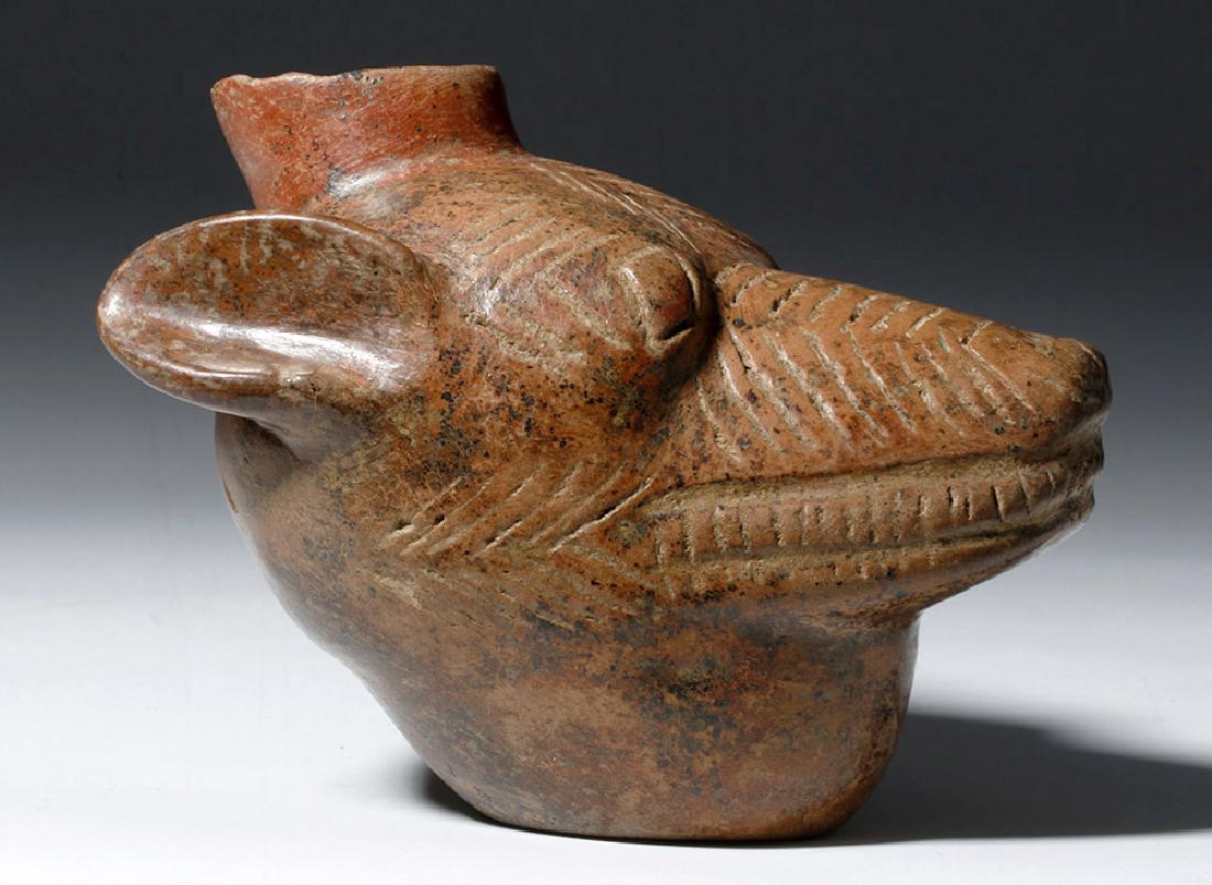 Colima Redware Vessel - Dog Head Form: Pre-Columbian, West Mexico, Colima, ca. 300 BCE to 300 CE. A red-brown pottery dog head with ears pinned back, incised facial markings, and with a wide spout extending from the top of the head. The do