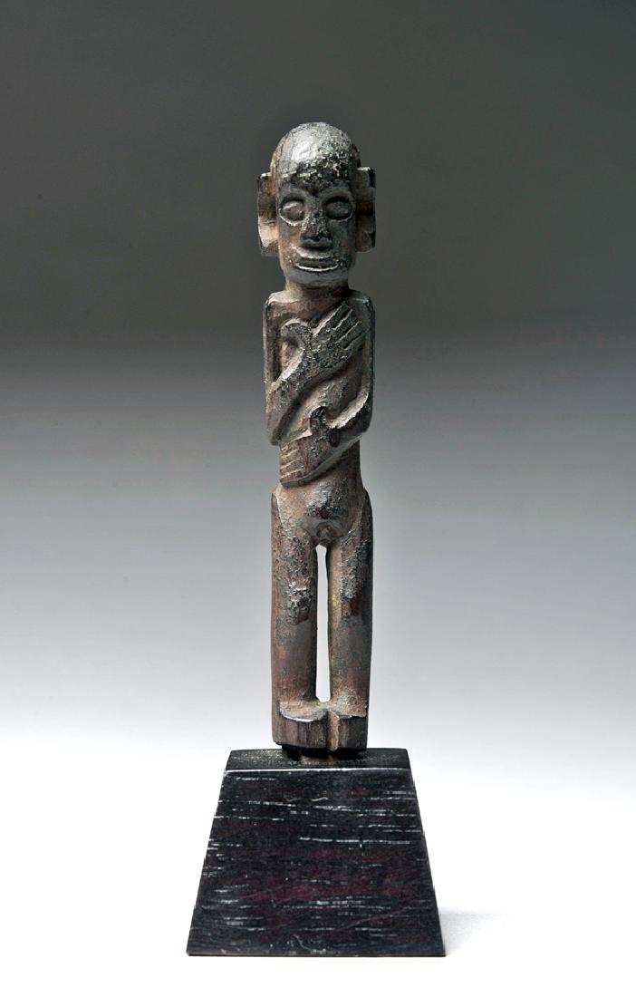 Borneo Tunjung Standing Shamanic Charm: Indonesia, Borneo, East Kalimantan, Tunjung tribe, early 20th century CE. A standing wooden shamanic charm figure with its arms wrapped around its body so that a hand is on the heart and another is on