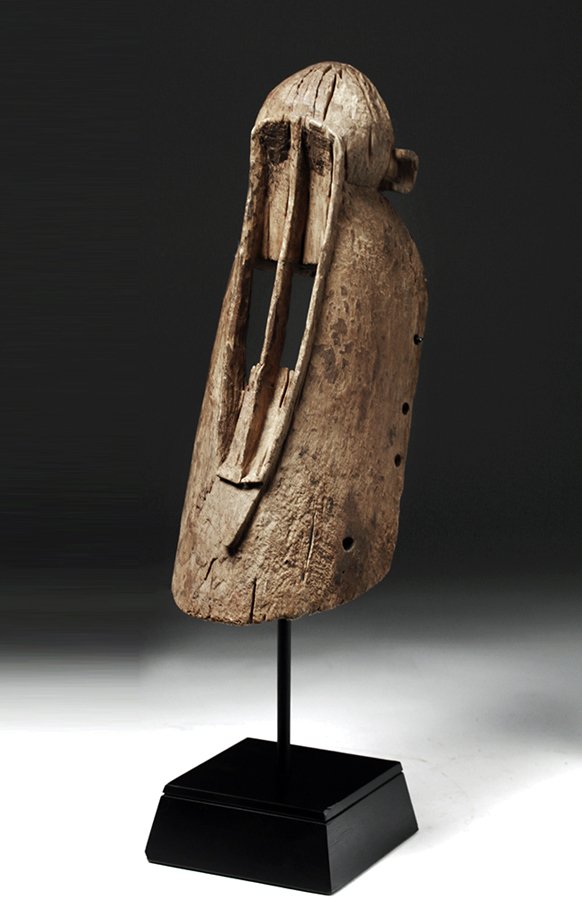 Early 20th C. Dogon Wooden Monkey Mask: Western Africa, Mali, Dogon people, ca. early 20th century CE. An abstract, hand-carved wooden mask in the form of a monkey with an elongated face and very long, open rectangular eyes. The top of the 