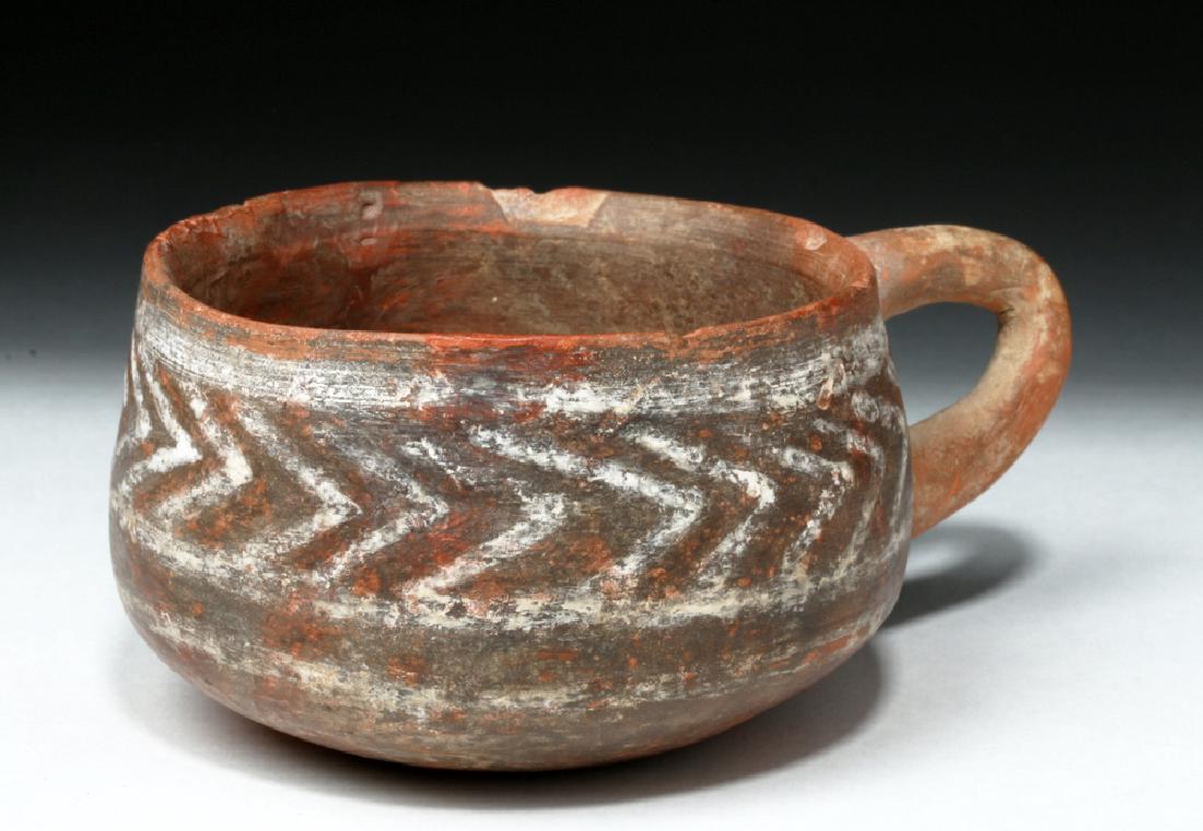 Rare Minoan Single-Handled Earthenware Cup: Ancient Mediterranean, Island of Crete, Minoan Civilization, ca. 1500 BCE. A petite terracotta vessel, in hues of burgundy and coral, with a flat stable base, curved side walls with a single applied h
