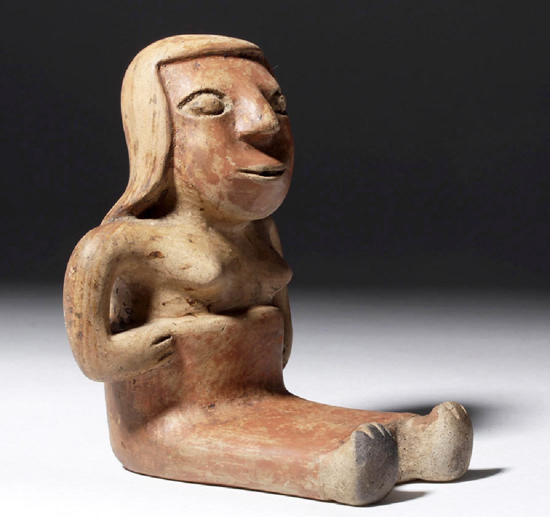 Narino Redware Seated Female - Coca Chewer: Pre-Columbian, Colombia, Narino culture, ca. 850 to 1500 CE. A seated pottery female wearing a long skirt, with her hands at her hips. The ingestion of coca is associated in ancient South American soc