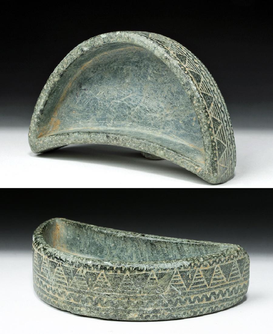 Fine Bactrian Schist Cosmetic Dish - Lunate Form: Central Asia, Bactrian, ca. 2500 to 2250 BCE. Skillfully carved from grey-green schist, an ornately incised vessel of a crescent moon shaped form, presenting vertical walls that are meticulously embel