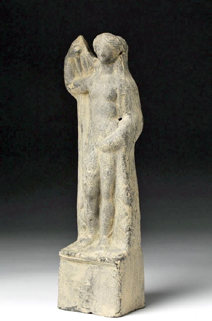 Greek Hellenistic Terracotta Aphrodite Votive: Greece, Hellenistic period, ca. 4th to 3rd centuries BCE. An earthenware votive figure of the goddess Aphrodite, mold-made and hollow. She stands on a cube pedestal, nude, with one hand resting on her