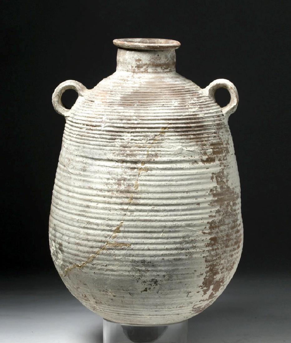 Roman Imperial Terracotta Transport Amphora: Rome, Imperial Period, ca. 200 CE. A transport amphora, coil-made, with sturdy loop handles attached to the shoulder and neck and a rolled rim. The base is rounded. Lacking its cork and pitch stopper,