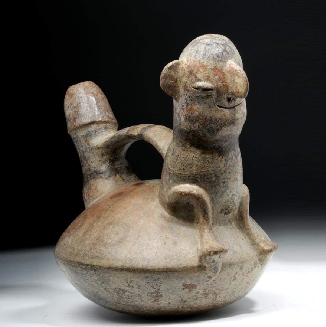 Vicus Erotic Pottery Stirrup Vessel - Phallic Spout: Pre-Columbian, North Coast Peru, Vicus, ca. 300 to 500 CE. A globular bottomed vessel with a graphically delineated phallic spout joined to a seated figure who presents an expressive visage comprised 