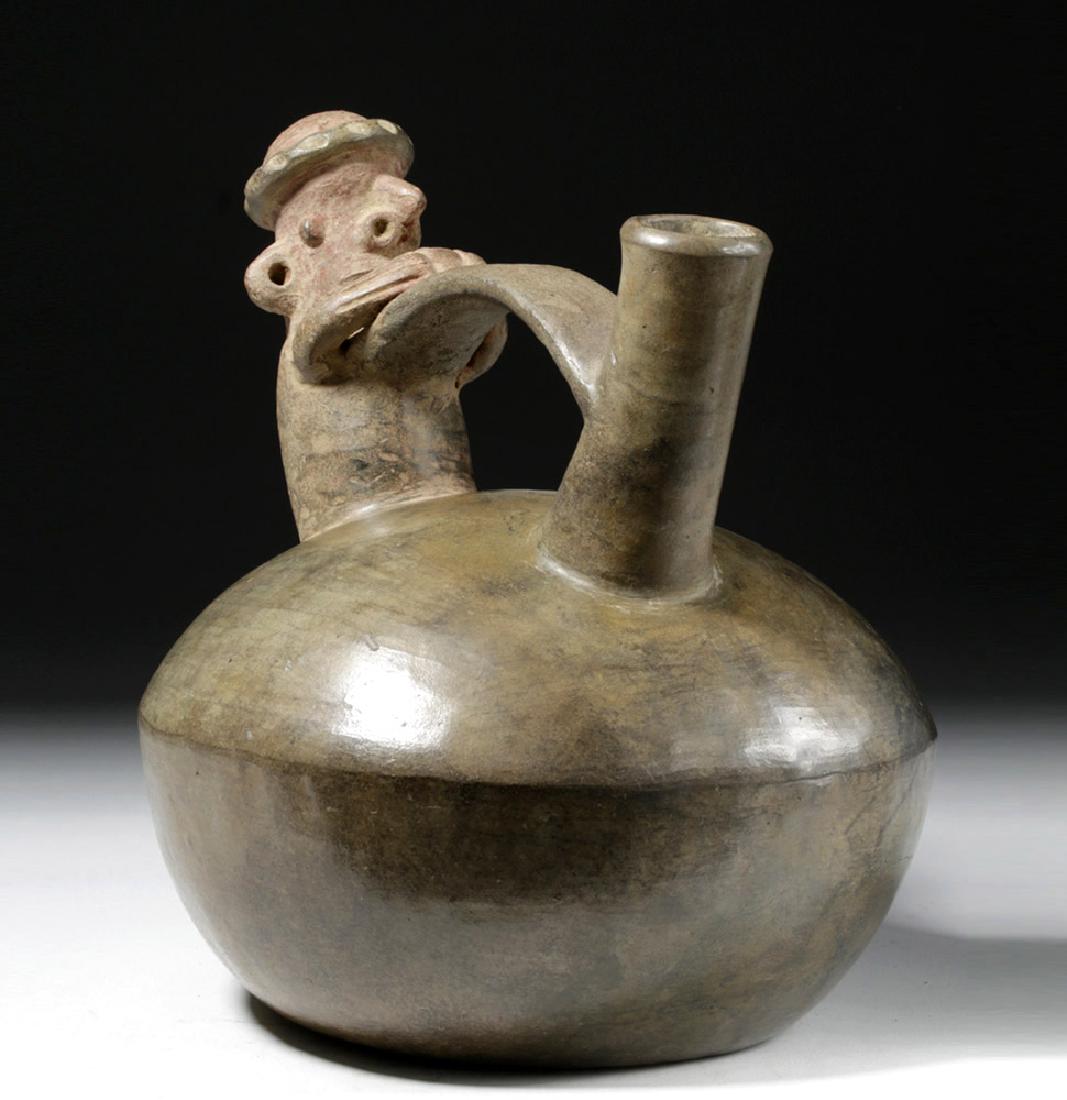 Vicus Pottery Whistling Bridge-Spouted Jar - Phallus: Pre-Columbian, North Coast Peru, Vicus, ca. 500 BCE to 500 CE. A handbuilt brownware whistling vessel, the body of a domed, rounded form, the bridge spout highlighting a phallic theme with a figure pr