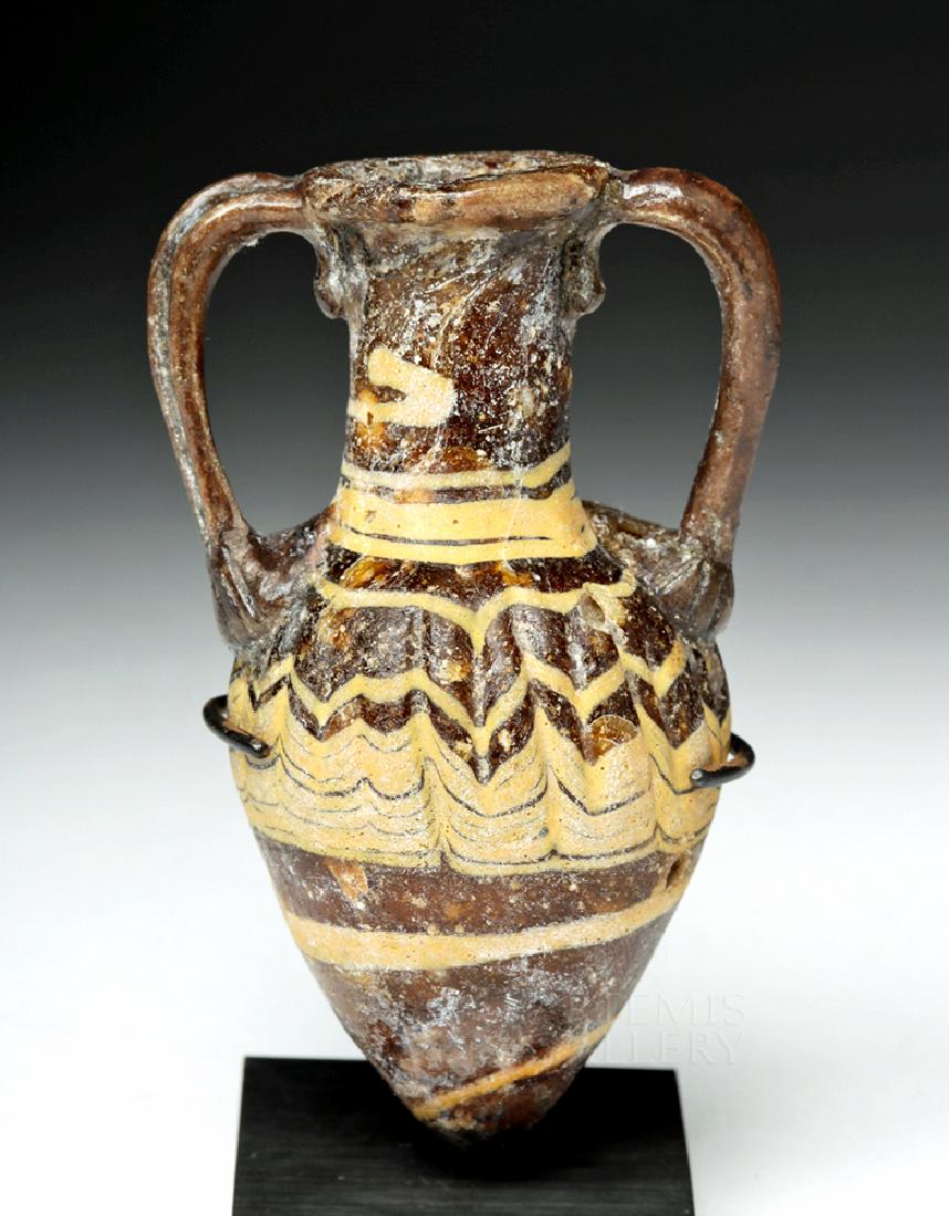 Hellenistic Greek Core-Formed Glass Amphoriskos: Ancient Greece, Hellenistic, ca. 3rd to 1st century BCE. An exquisite core-formed glass amphoriskos (miniature amphora) once used to hold perfumed oil. This near miniature vase boasts an exceptionally
