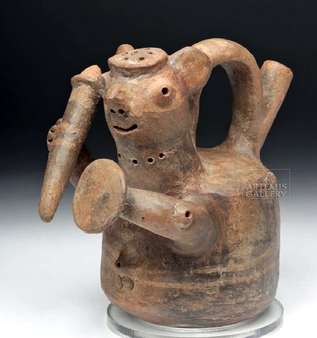 Vicus Whistling Pottery Warrior Stirrup Vessel: Pre-Columbian, North Coast Peru, Vicus, ca. 400 to 100 BCE. A handbuilt earthenware warrior effigy whistling stirrup vessel presenting the warrior's head at the front end of the stirrup with bold appl