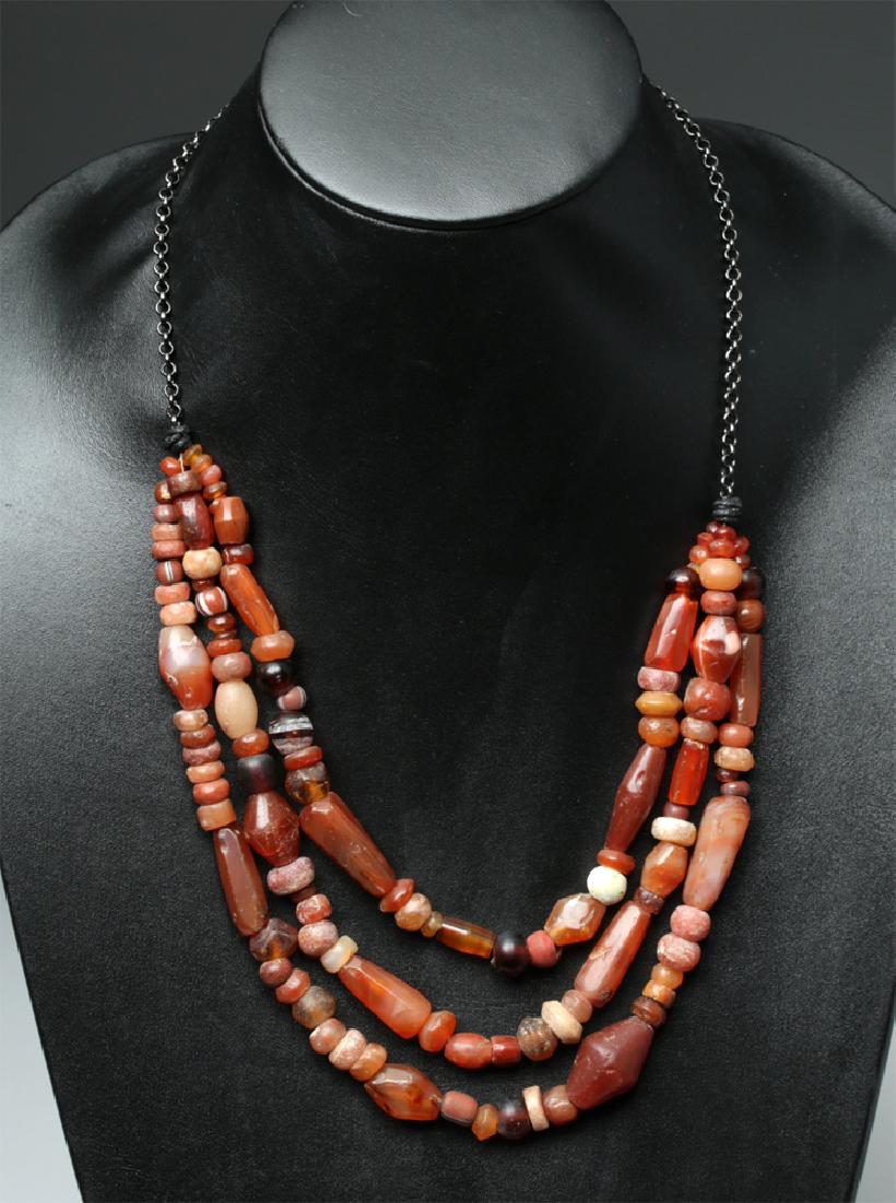 Viking Carnelian Bead Layered Necklace: Northern Europe, Viking / Norse, ca. 8th to 11th century CE. A sparkling, three-stranded necklace, composed of over fifty carnelian beads of all different shapes, some round, some diamond-shaped, some