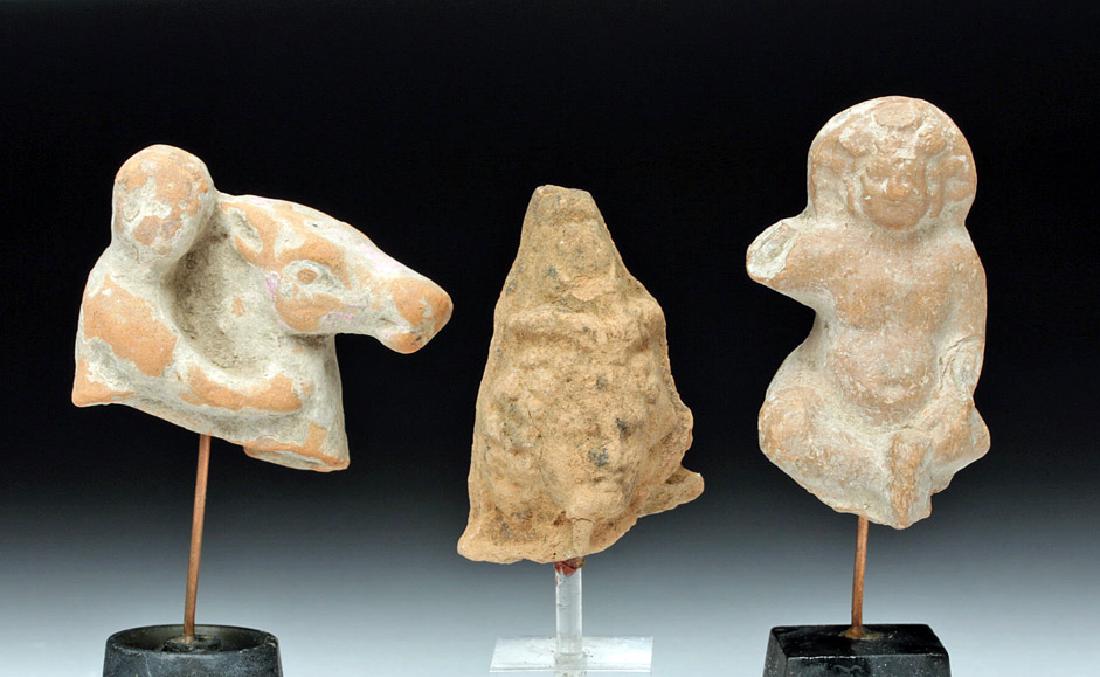 Lot of 3 Romano-Egyptian Terracotta Votives: Egypt, Romano-Egyptian period, ca. 1st century BCE to 1st century CE. A trio of mold-made earthenware votives. The first depicts a horse and rider; the second the head of the child god Harpocrates wit