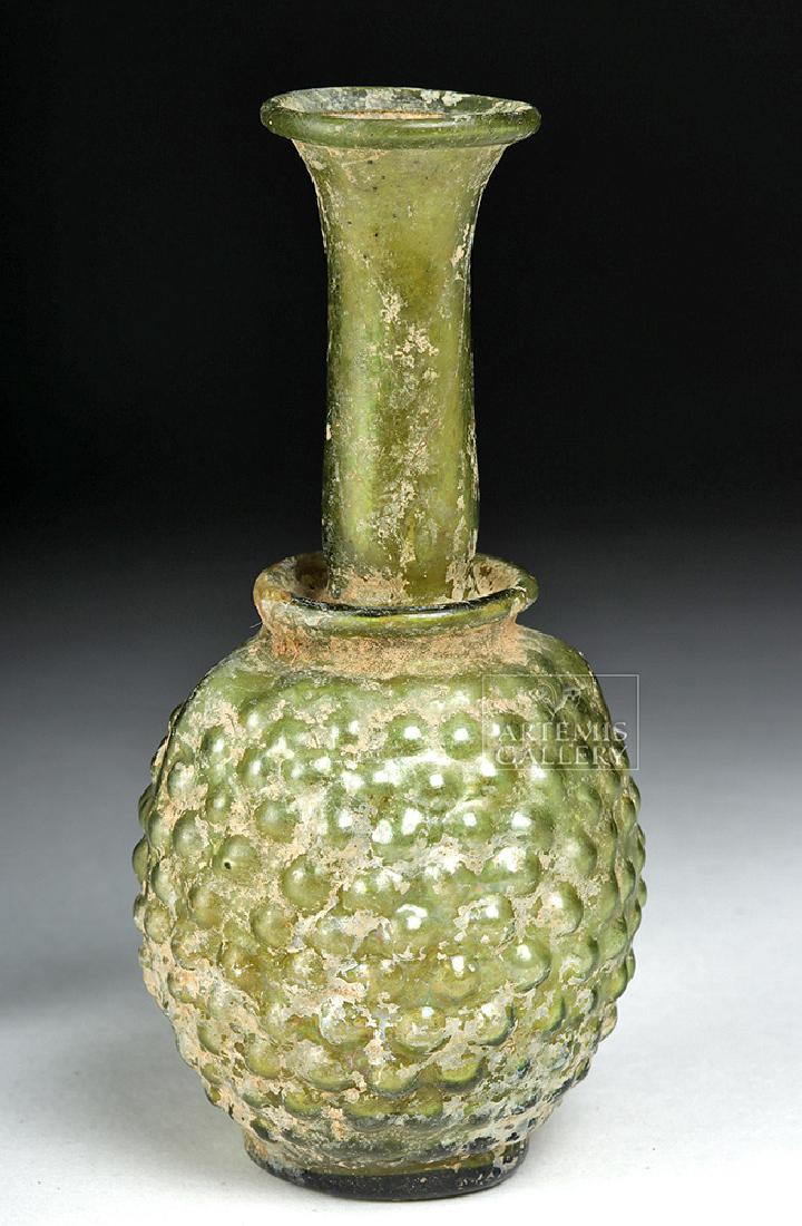 Roman Glass Unguentarium - Rows of Stylized Grapes: Roman, Imperial Period, ca. 2nd to 3rd century CE. A beautiful mold-blown Roman glass unguent-holding bottle with a flat base and a slightly-rough pontil. The textured body exhibits eleven rows of sty