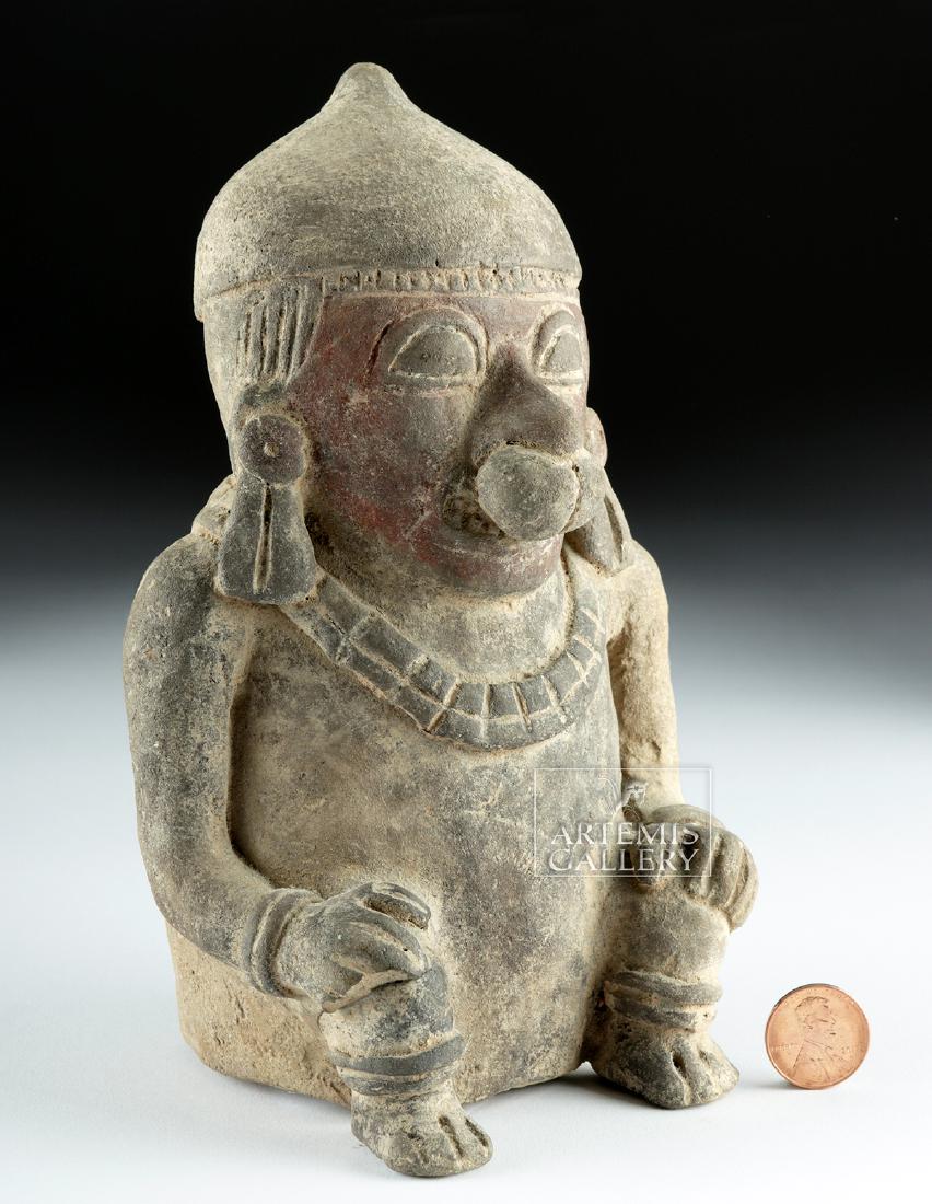 Fine Manabi Terracotta Seated Figure: Pre-Columbian, Ecuador, Manabi Province, Manabi culture, ca. 500 CE. A fine hollow-cast terracotta figure seated upon a planar base with hands resting on bent knees. A broad torso traces upwards to ro