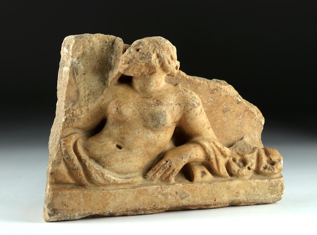 Roman Marble Sarcophagus Fragment: Roman, Imperial Period, ca. 2nd to 3rd century CE. Lovely marble section most likely from a sarcophagus. A somewhat sensuous relief of a reclining semi-nude female banqueter; she lays with her weight 