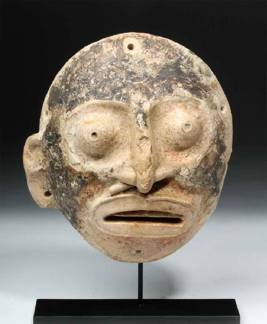 Mayan Toltec Limestone Mask w/ Black Pigment: Pre-Columbian, central Mexico, Maya / Toltec, ca. 900 to 1200 CE. A wide-eyed mask carved from limestone with bulging eyes, a strong nose, and a wide mouth with huge lips. The face is colored with bla