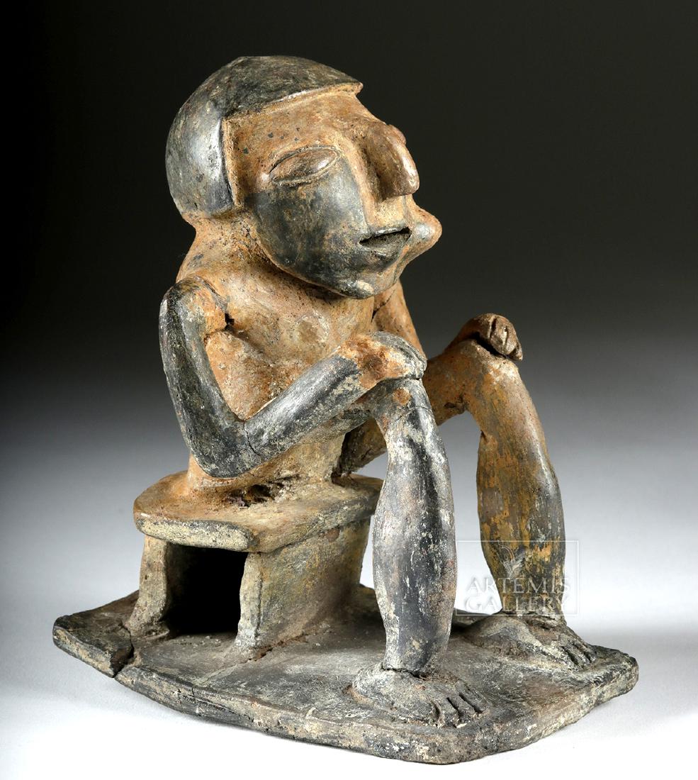 Narino Bichrome Seated Coquero (Coca Chewer): Pre-Columbian, Ecuador/Colombia, Carchi-Narino region, ca. 750 to 1500 CE. A charming and rare ceramic sculpture of a seated coca chewer. He sits on a stool, part of an integrated plaque, his long, sp