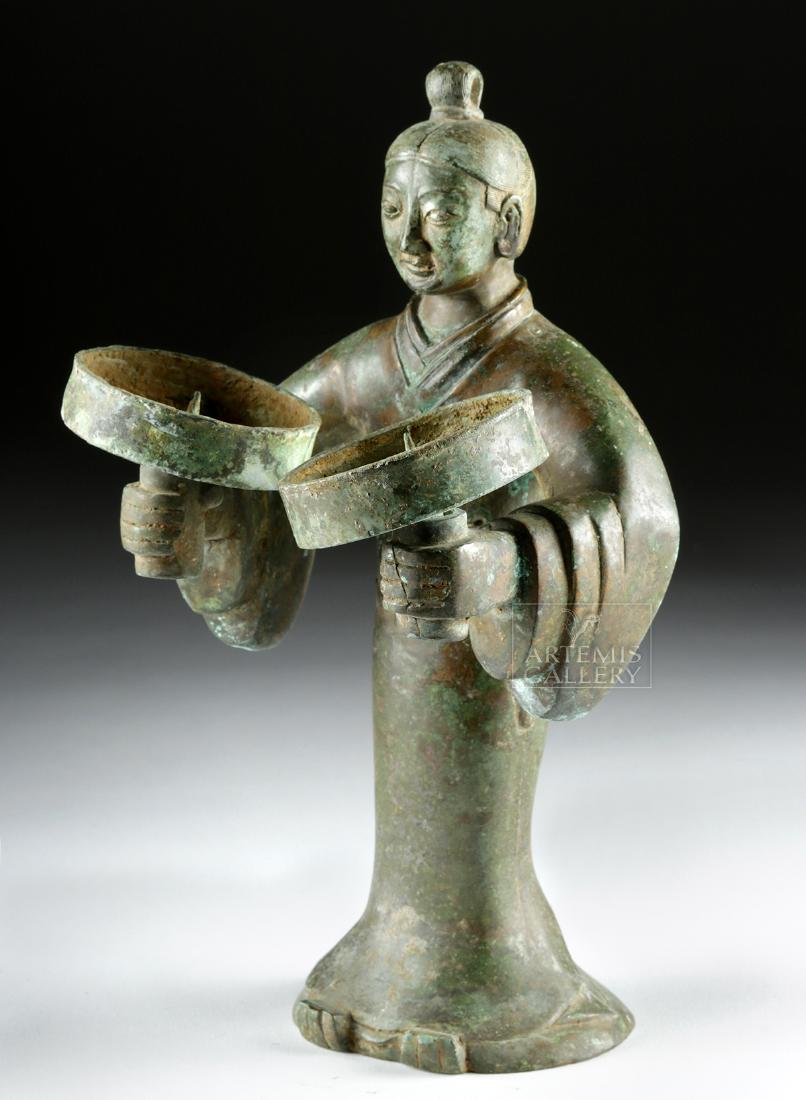 Chinese Qing Bronze Figural Lamp / Candle Holder: East Asia, China, Qing Dynasty, ca. 1644 to 1911 CE. A cast bronze candleholder or oil lamp in the form of a standing figure donning a long robe with a weapon secured in the belt, facing forward with 