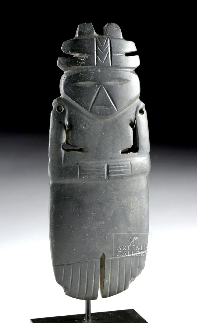 Exhibited Costa Rican Stone Anthropomorphic Celt: Pre-Columbian, Central America, Costa Rica, ca. 500 to 800 CE. An excellent celt, hand-carved from a charcoal-grey stone, depicting a highly-stylized anthropomorphic figure standing atop delineated le