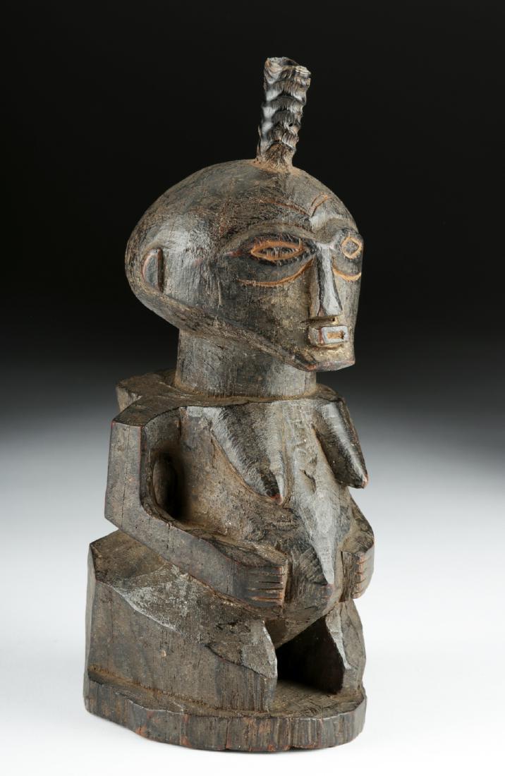 Early 20th C. Songye Wood Female Figure w/ Wood Horn: Central Africa, Democratic Republic of the Congo, Songye culture, ca. early to mid 20th century CE. A stylized anthropomorphic female figure, hand-carved from hard wood, depicted standing with thick, 