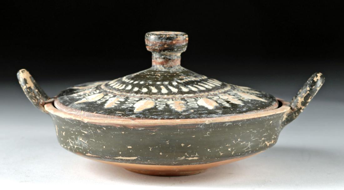 Gnathian Ceramic Lidded Lekanis: Magna Graecia, southern Italy, Apulia, ca. 340 to 325 BCE. A charming terracotta vessel used to store soaps and scented perfumes, with a thin-walled body, twin handles, and a slightly raised disc base