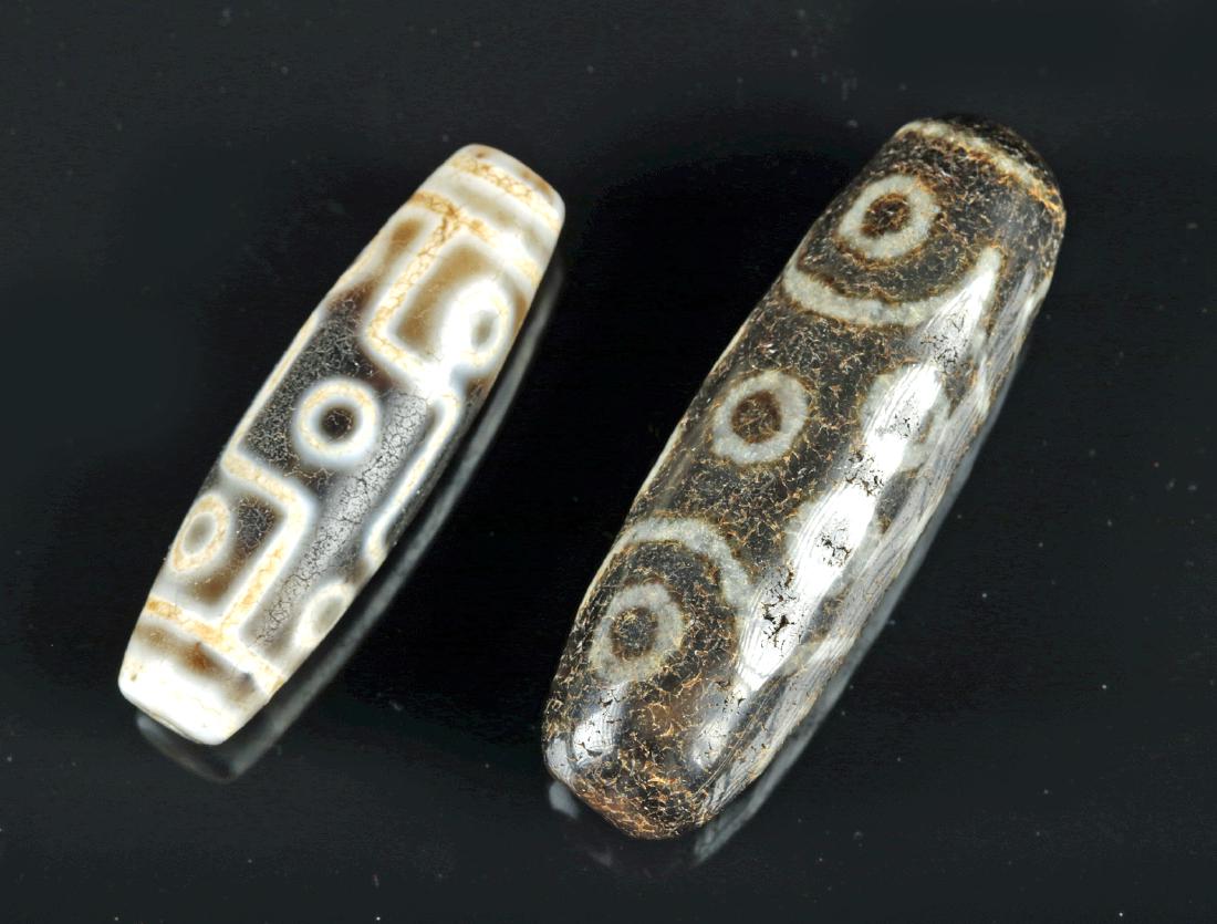 Lot of 2 Early Tibetan Agate dZi Beads: Central Asia, Tibet, ca. 1st millennium BCE. A pair of two dZi beads, each deep brown-etched-on-white agate stone dZi bead, with highly abstract motifs of circles and either curving or straight lines 