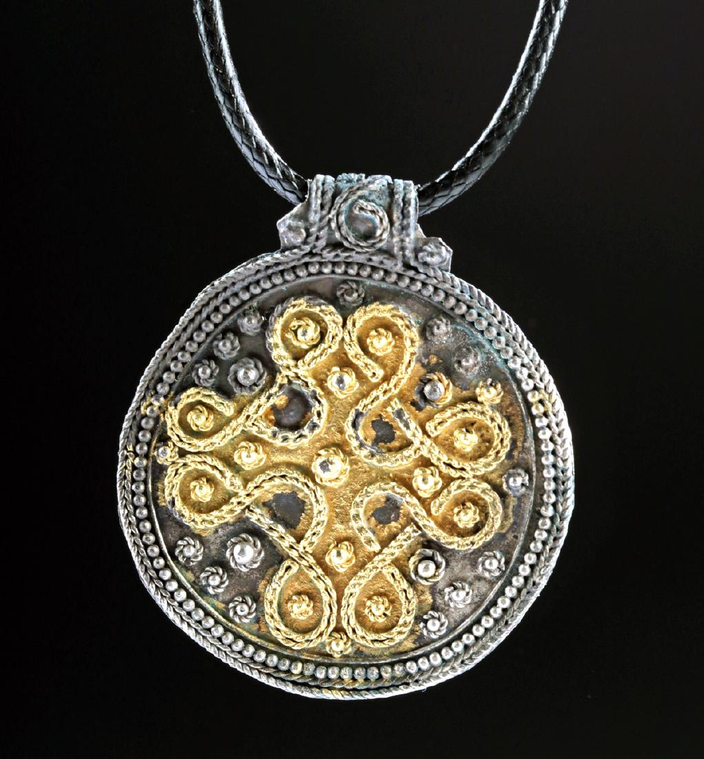 Fabulous Viking Gilded Silver Filigree Pendant: Northern Europe, Viking or Norse culture, ca. 9th to 11th century CE. A fabulous pendant of a circular form with an integral suspension bar folded behind the verso, shaped from a hammered sheet of sil