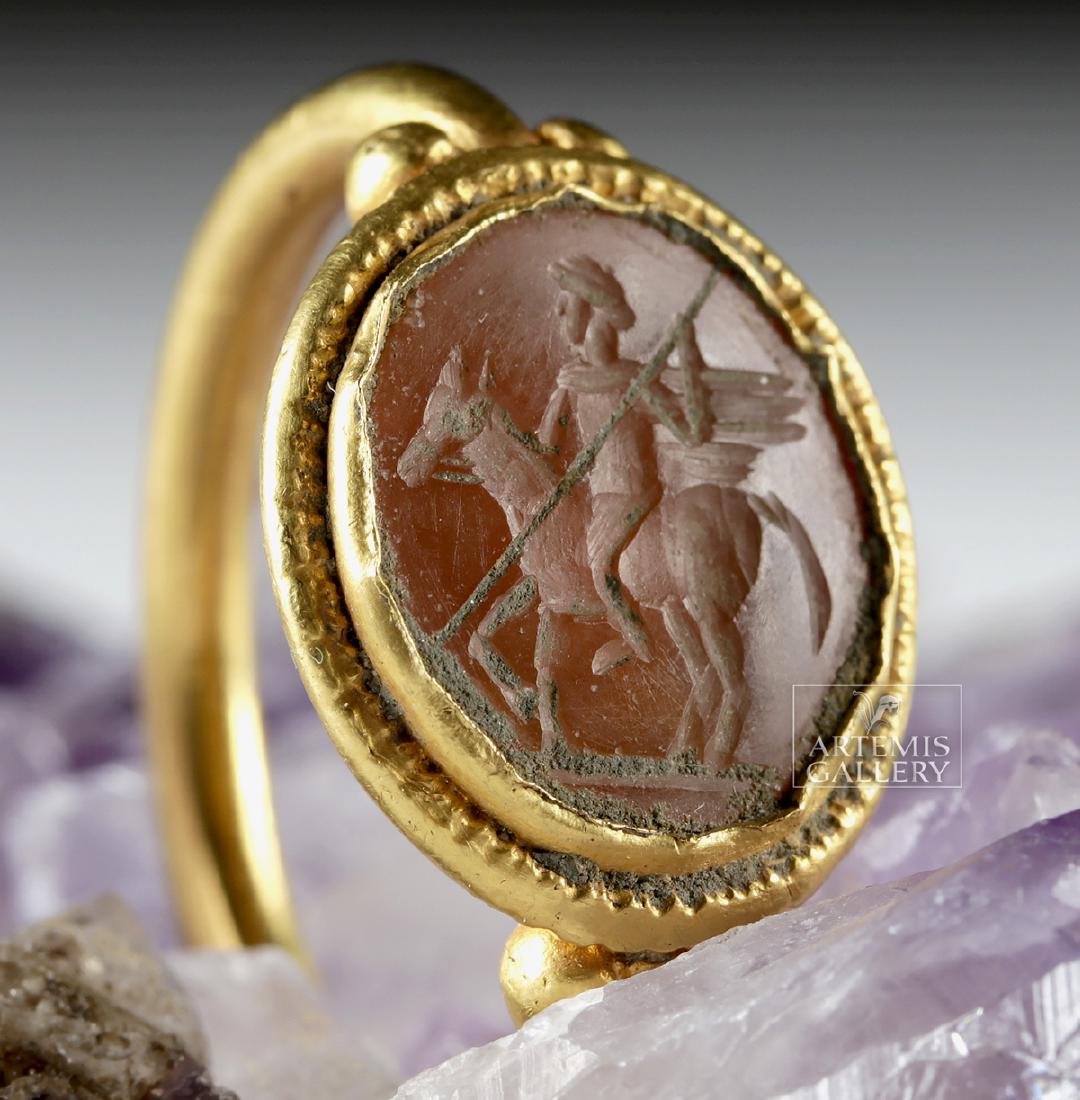 Roman 20K+ Gold Ring w/ Carnelian Intaglio Equestrian: Roman, Imperial Period, ca. 1st to 3rd century CE. A stunning gold ring comprised of 89% gold (equivalent to 20K+) and set with a large oval carnelian intaglio of warm orange hues depicting a horse an