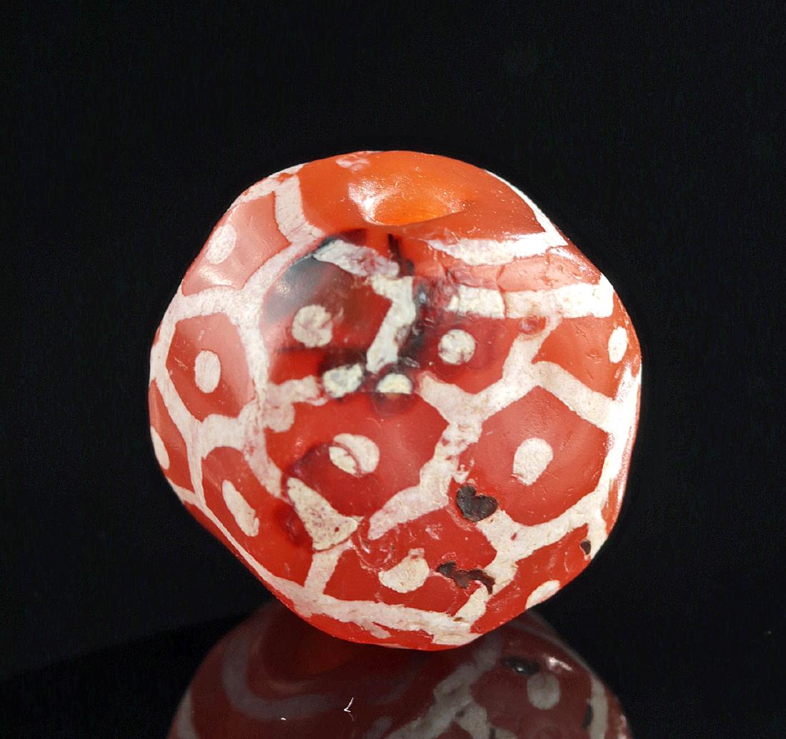 Fine Bactrian Etched Carnelian Bead: Ancient Central/Western Asia, Bactrian Empire, ca. 1st millennium BCE. A beautiful hand-carved carnelian bead of a round tablet-like shape, etched with a white honeycomb-like design that makes a marve