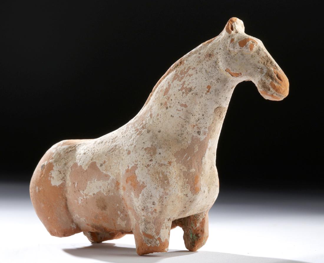 Chinese Tang Terracotta Horse: East Asia, China, Tang Dynasty, ca. 618 to 907 CE. A hollow, mold-formed earthenware horse with a muscular body (missing legs), a raised head boasting perky ears and a thick snout, and a petite tail. 