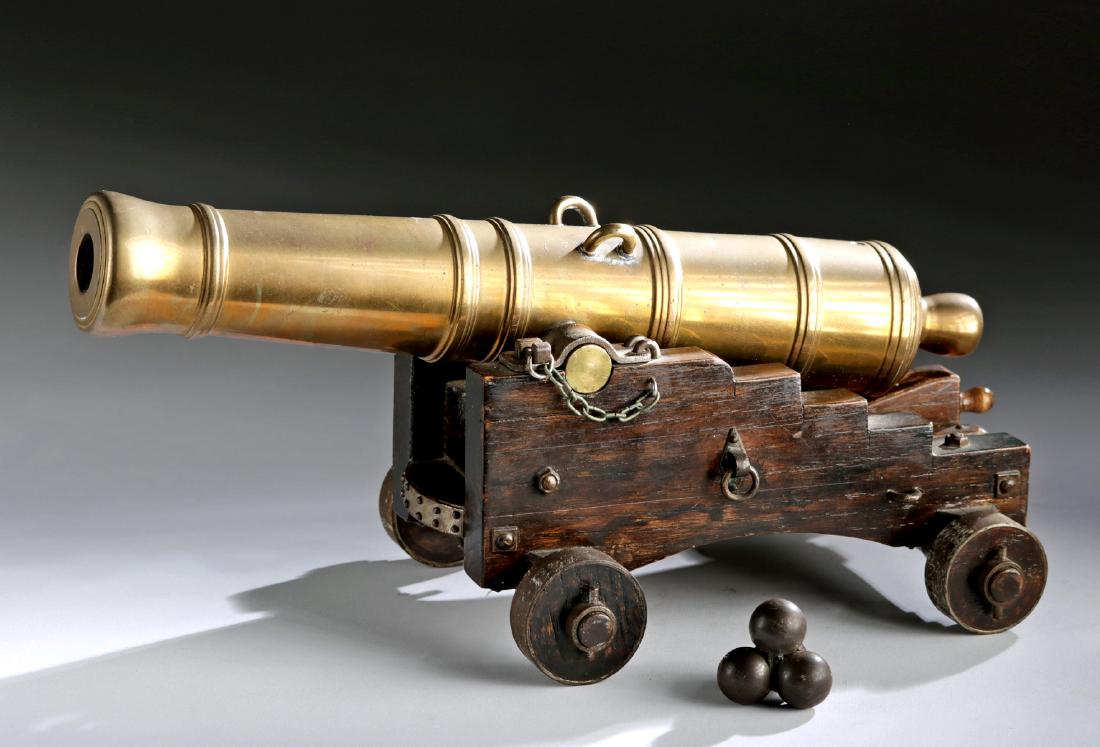 20th C. USA Miniature Brass Cannon w/ Cannonball Stack: North America, USA, ca. 1960s CE. A handsome, heavy, brass cannon with a small steel cannonball stack, all made by a US Navy machinist. The cannon sits on a wooden rolling frame. Size: 13" W x 6.2" H 